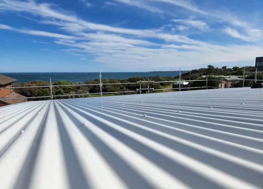 Aerial-view-of-a-house-featuring-a-distinctive-metal-roof-1920w Corrugated metal roof under repair in a sunny beachside town.