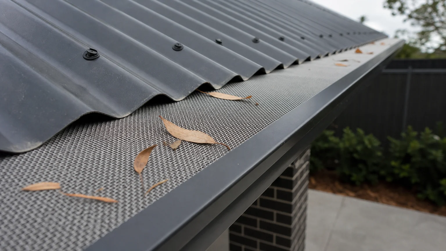Metal mesh gutter guard installed beneath a corrugated roof